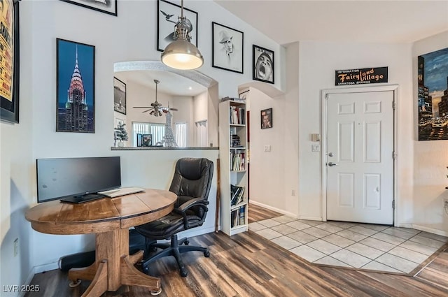 office featuring arched walkways, wood finished floors, a ceiling fan, and baseboards