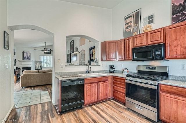 kitchen with light countertops, a sink, light wood-style floors, black appliances, and ceiling fan