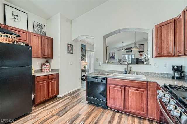 kitchen with a sink, arched walkways, vaulted ceiling, a ceiling fan, and black appliances