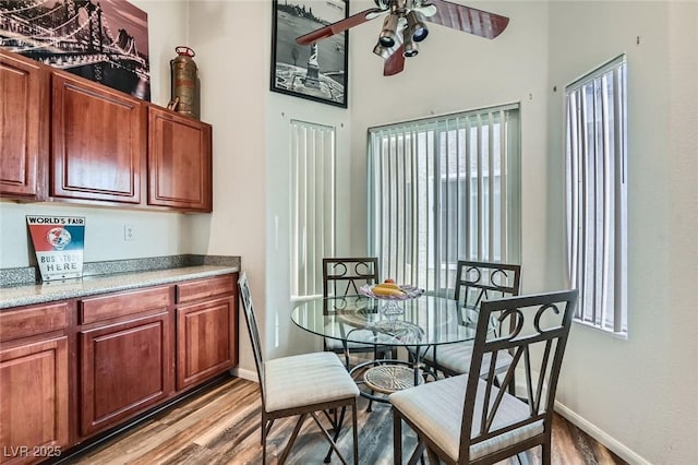 dining area with light wood-type flooring, a ceiling fan, and baseboards