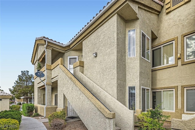 view of side of property featuring stucco siding and a tile roof
