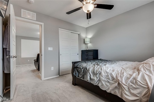 bedroom with baseboards, visible vents, light colored carpet, a ceiling fan, and a closet