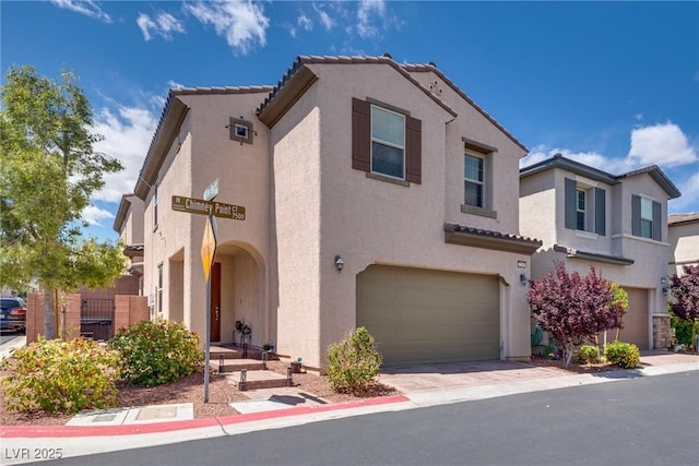 mediterranean / spanish house with stucco siding, an attached garage, and a tiled roof