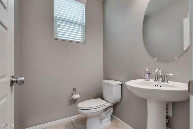 bathroom with baseboards, tile patterned flooring, a sink, and toilet