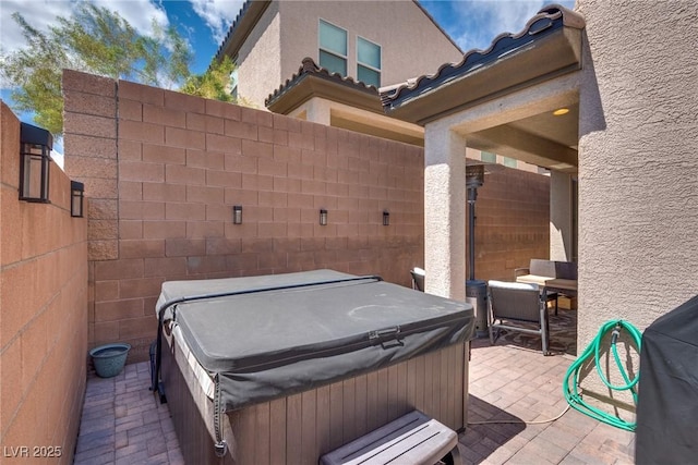 view of patio / terrace with a hot tub and fence