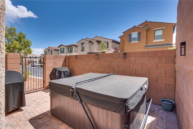 exterior space with a grill, a hot tub, a residential view, and fence