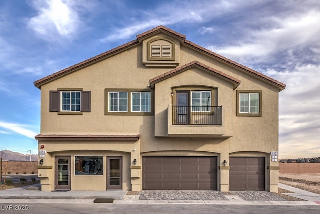 view of front of home featuring an attached garage, a tiled roof, decorative driveway, and stucco siding