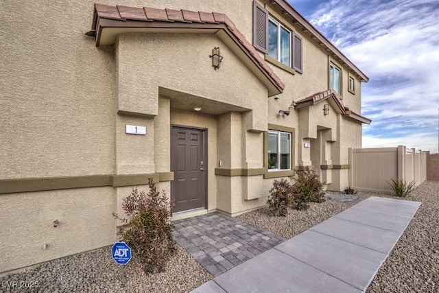 property entrance featuring stucco siding and fence