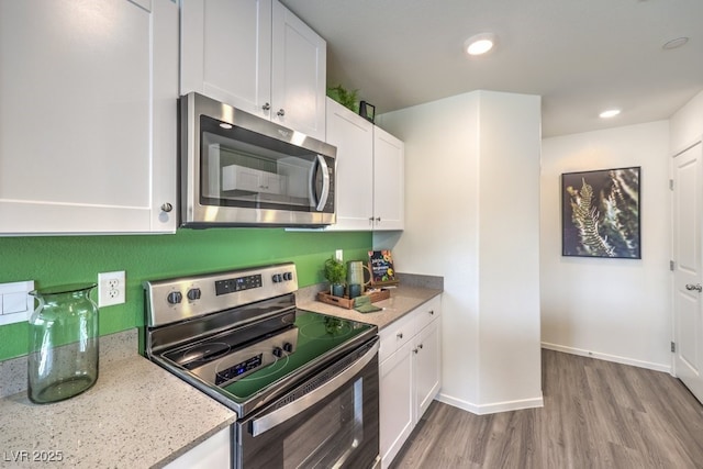 kitchen with white cabinets, stainless steel appliances, wood finished floors, and recessed lighting