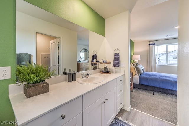 bathroom with visible vents, wood finished floors, connected bathroom, and vanity