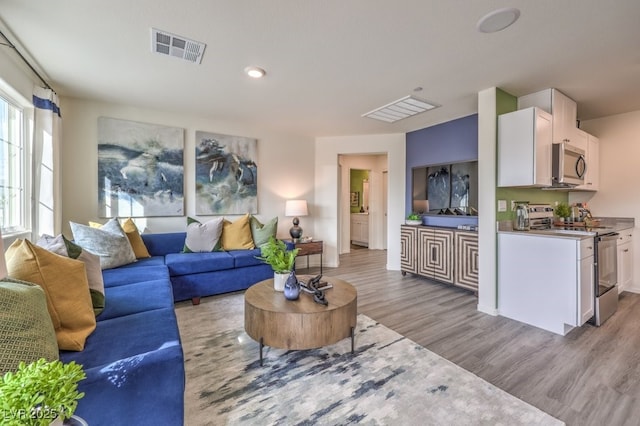 living area featuring light wood-style floors and visible vents