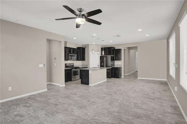 10976 Bluebell Basin Rd, Las Vegas, NV 89179 - kitchen featuring stainless steel appliances, open floor plan, dark cabinets, light countertops, and an island with sink