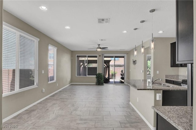 10976 Bluebell Basin Rd, Las Vegas, NV 89179 - kitchen with a sink, ceiling fan, baseboards, light stone counters, and open floor plan