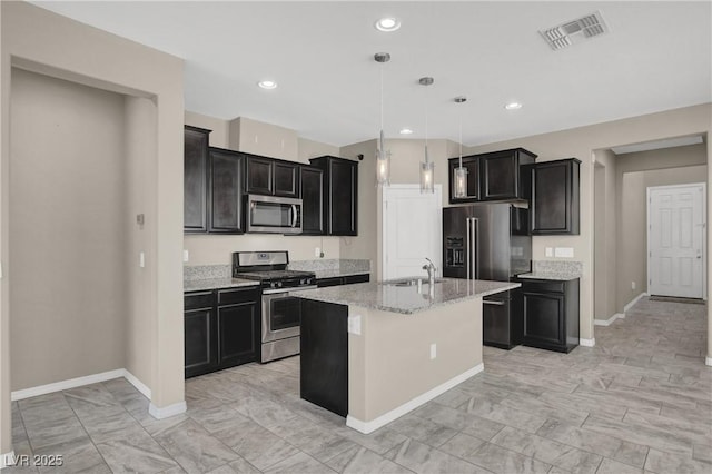 10976 Bluebell Basin Rd, Las Vegas, NV 89179 - kitchen with stainless steel appliances, baseboards, a sink, light stone countertops, and dark cabinetry