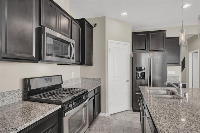 10976 Bluebell Basin Rd, Las Vegas, NV 89179 - kitchen featuring stainless steel appliances, a sink, light stone countertops, pendant lighting, and baseboards