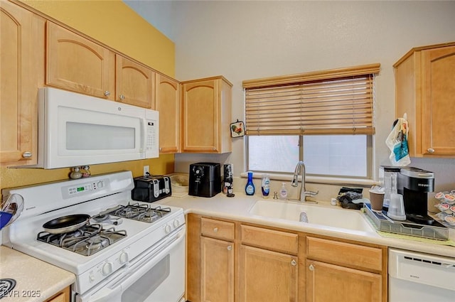 kitchen featuring light countertops, light brown cabinets, a sink, and white appliances