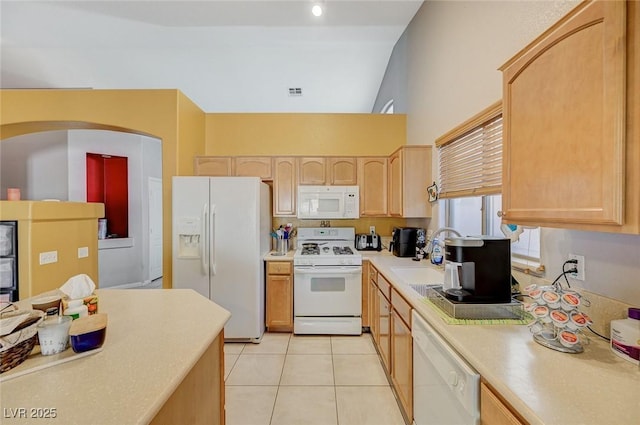 kitchen with light brown cabinets, a sink, white appliances, light tile patterned floors, and light countertops