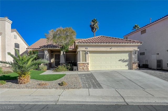 mediterranean / spanish house with concrete driveway, stone siding, a tiled roof, a garage, and stucco siding