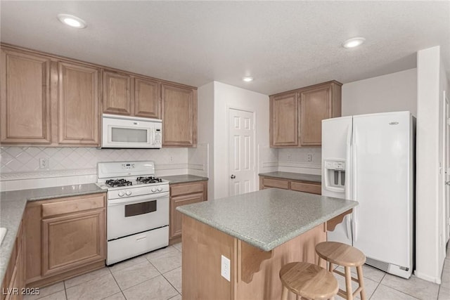 519 Brinkburn Point Ave, Las Vegas, NV 89178 - kitchen featuring tasteful backsplash, white appliances, a breakfast bar area, a center island, and light tile patterned flooring