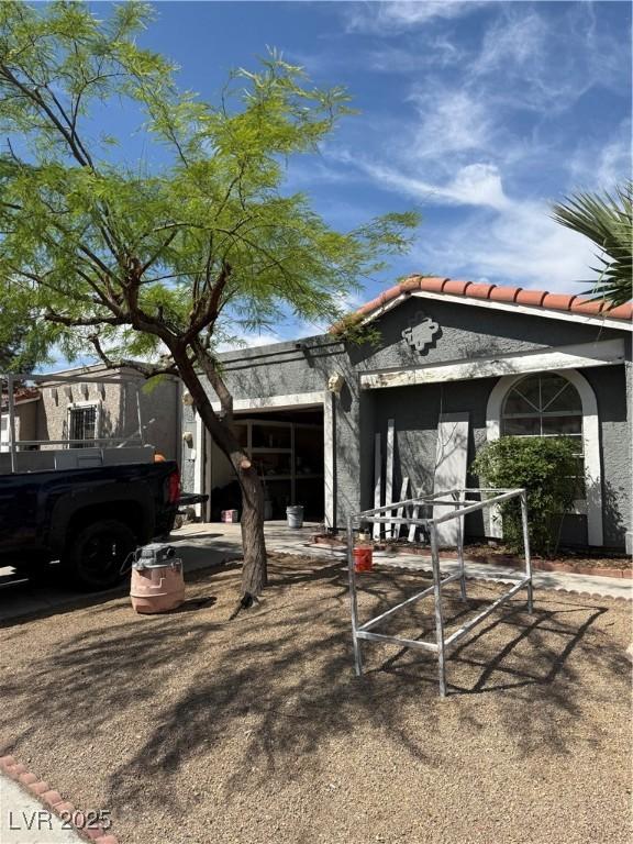view of front of house featuring stucco siding, a tiled roof, and a garage