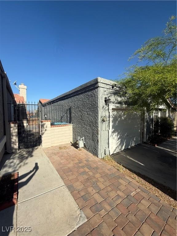 view of patio featuring fence, a gate, and a garage