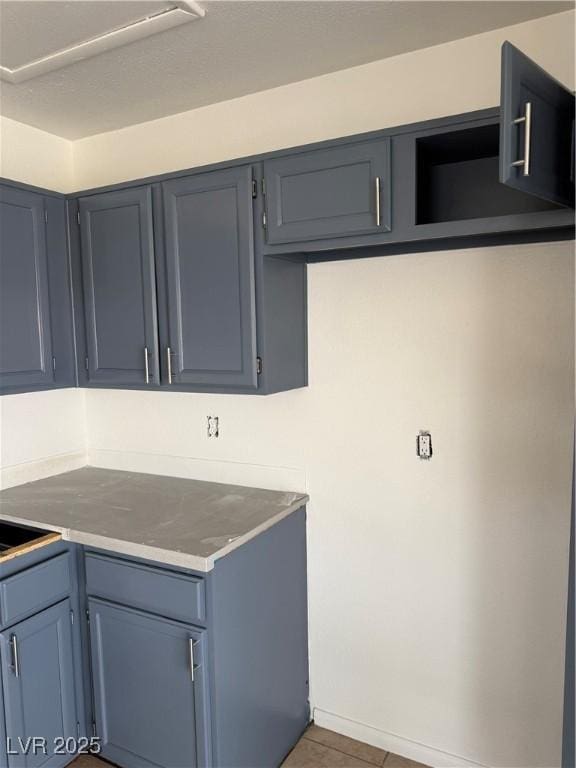 kitchen featuring light countertops, tile patterned floors, baseboards, and blue cabinets
