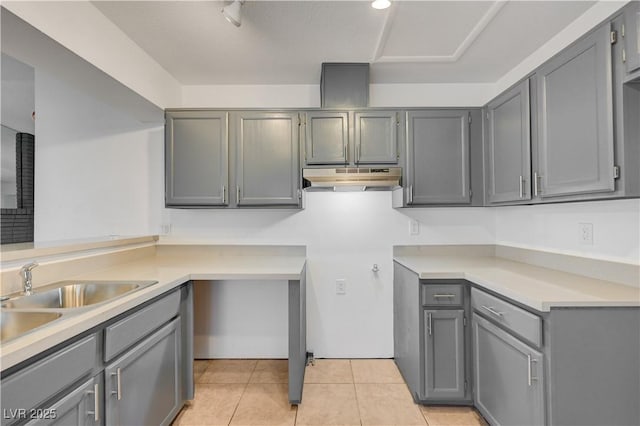 2377 Los Feliz St, Las Vegas, NV 89156 - kitchen featuring gray cabinetry, under cabinet range hood, light tile patterned floors, a sink, and light countertops