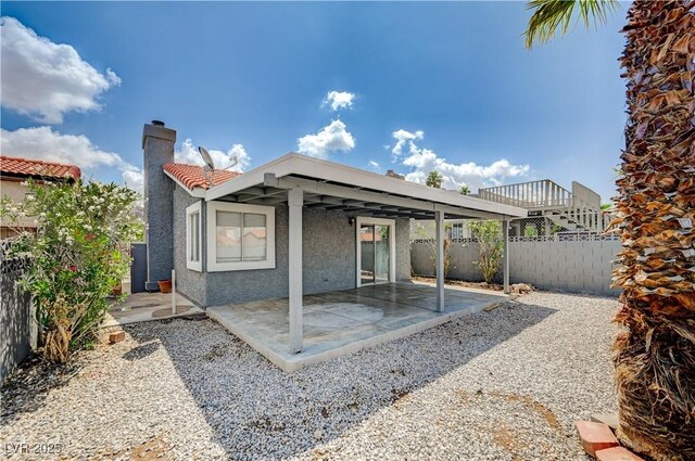 2377 Los Feliz St, Las Vegas, NV 89156 - rear view of house with stucco siding, a patio, a chimney, a fenced backyard, and a tile roof