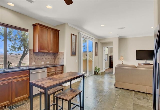 kitchen featuring dark countertops, tasteful backsplash, a sink, dishwasher, and recessed lighting