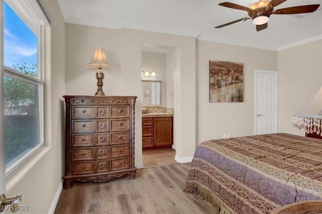 bedroom featuring baseboards, ensuite bath, ceiling fan, and light wood-style flooring