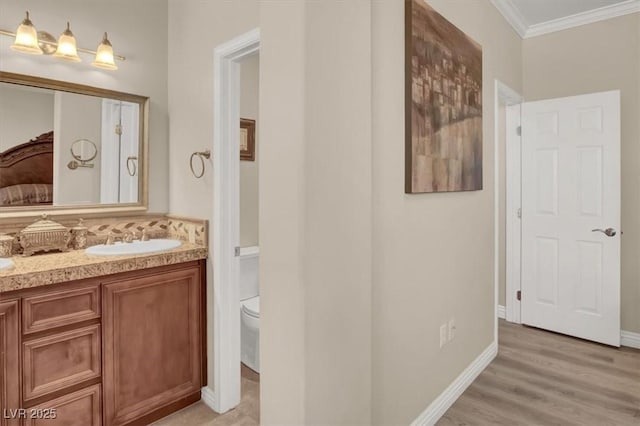 full bath with toilet, baseboards, wood finished floors, vanity, and ornamental molding