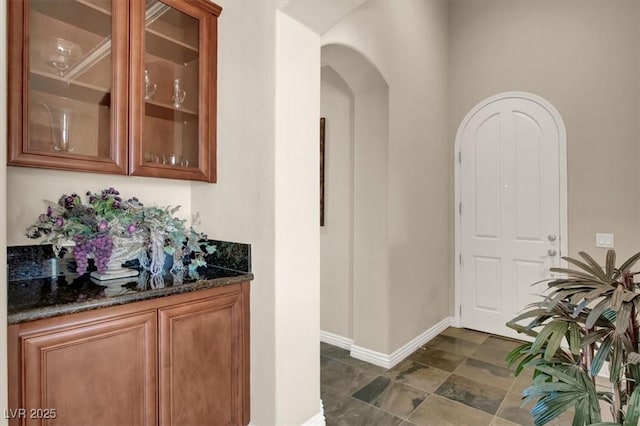 bar featuring arched walkways, stone finish flooring, and baseboards