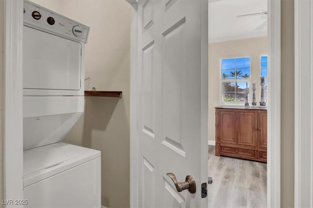 washroom featuring laundry area, stacked washing maching and dryer, and light wood finished floors