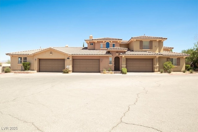 mediterranean / spanish-style house featuring a tile roof, driveway, a chimney, a garage, and stucco siding