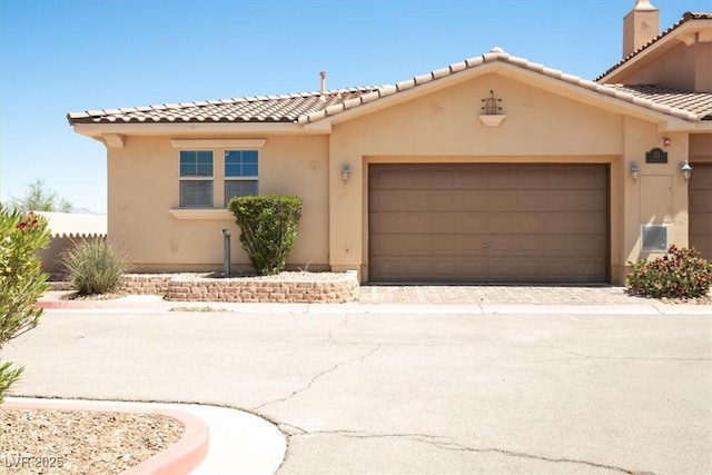 view of front of home featuring stucco siding, driveway, a tiled roof, and a garage