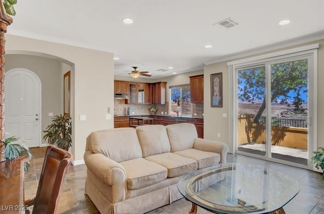 living area featuring arched walkways, baseboards, visible vents, recessed lighting, and ceiling fan