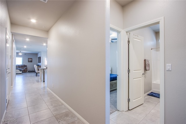 corridor featuring baseboards, light tile patterned flooring, and recessed lighting