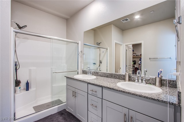 full bath with a walk in closet, a shower stall, visible vents, and a sink