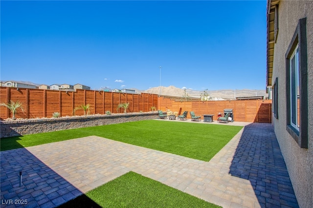 view of yard with a patio area, a fenced backyard, and a mountain view