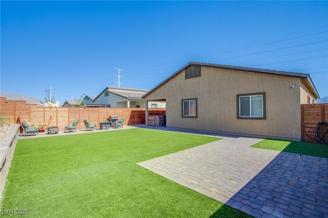 rear view of house with a fenced backyard, a patio, and a lawn