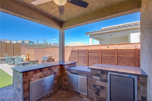 view of patio / terrace with fence, a ceiling fan, beverage cooler, and area for grilling