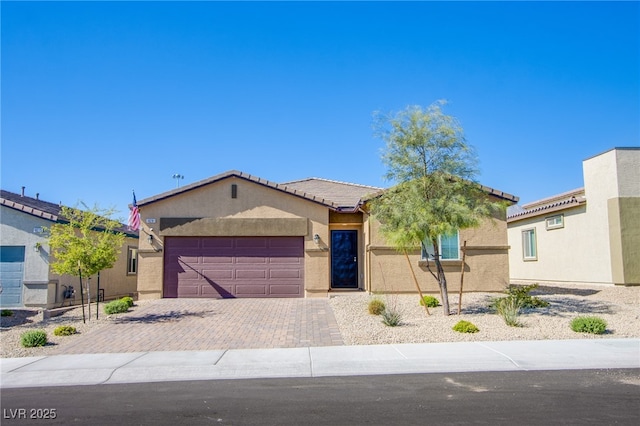 ranch-style home featuring a garage, a tile roof, decorative driveway, and stucco siding