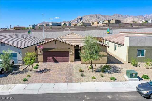 single story home with a tiled roof, a residential view, stucco siding, an attached garage, and a mountain view