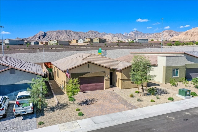 view of front of home with driveway, a tiled roof, an attached garage, a mountain view, and stucco siding