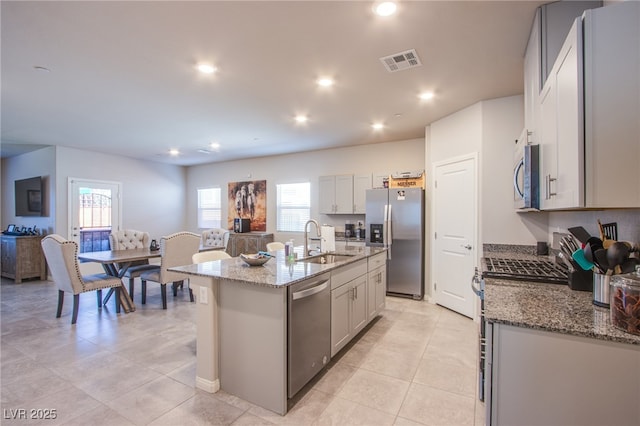 kitchen featuring a sink, plenty of natural light, stone counters, visible vents, and appliances with stainless steel finishes