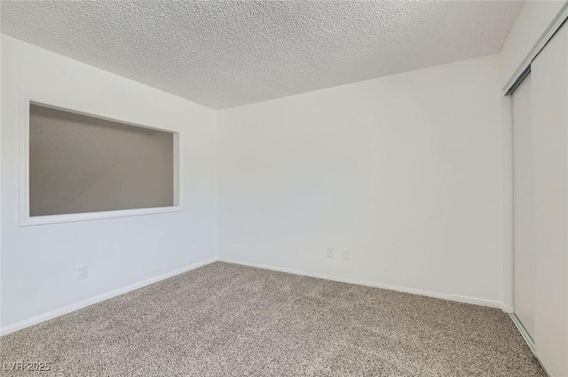 empty room featuring baseboards, carpet floors, and a textured ceiling