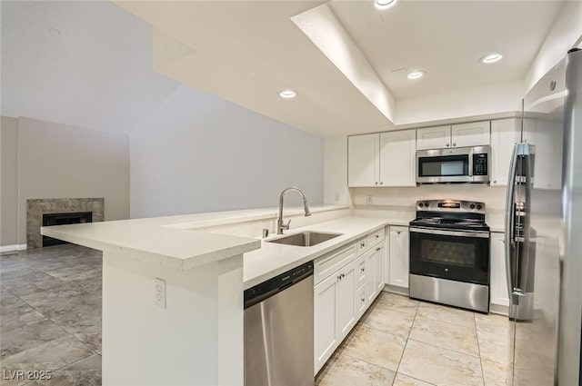 kitchen featuring a peninsula, a sink, recessed lighting, light countertops, and appliances with stainless steel finishes