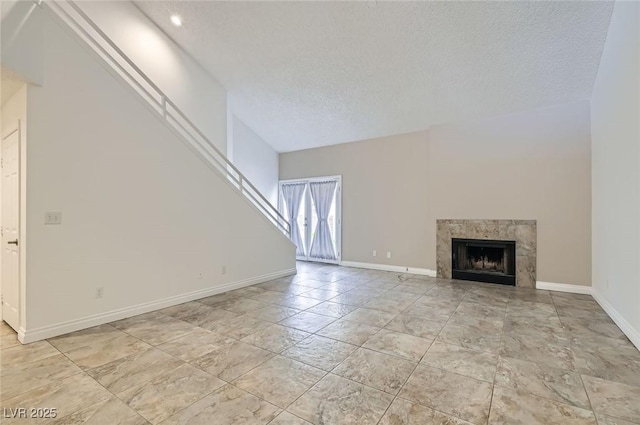 unfurnished living room featuring baseboards, a fireplace, and a textured ceiling