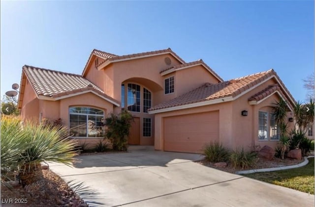 mediterranean / spanish house with concrete driveway, a tiled roof, a garage, and stucco siding