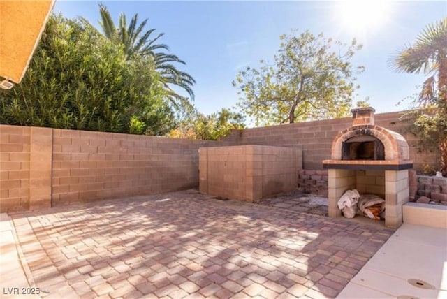view of patio featuring a fenced backyard and an outdoor brick fireplace